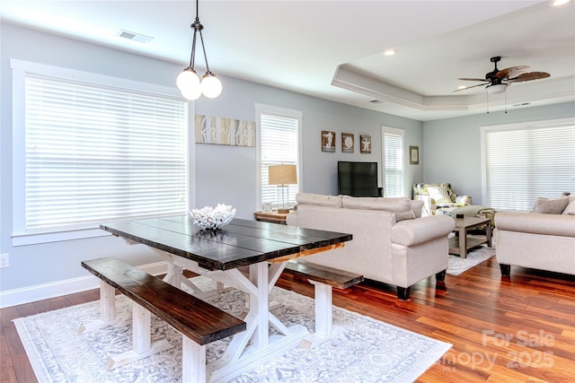 dining room featuring a raised ceiling, dark hardwood / wood-style floors, and ceiling fan