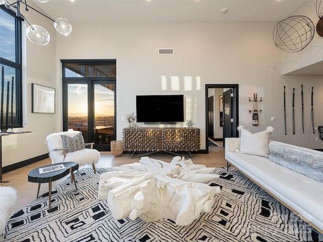 living room with a towering ceiling, baseboards, visible vents, and wood finished floors