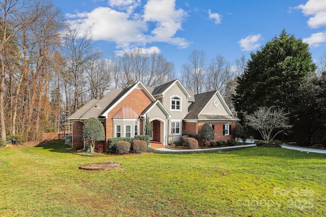 traditional-style house featuring brick siding, a front yard, and stucco siding