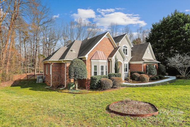 view of side of property featuring a yard, fence, and brick siding