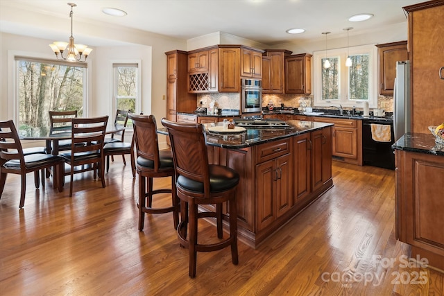 kitchen with black dishwasher, hanging light fixtures, brown cabinetry, and a kitchen island