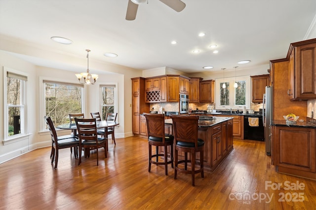 kitchen featuring brown cabinetry, a center island, stainless steel appliances, and hanging light fixtures