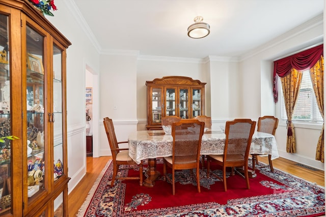 dining space featuring ornamental molding, visible vents, baseboards, and wood finished floors