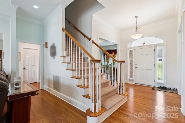 entryway featuring ornamental molding, wood finished floors, visible vents, and baseboards