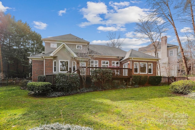 view of front of house featuring a front yard, brick siding, fence, and a wooden deck