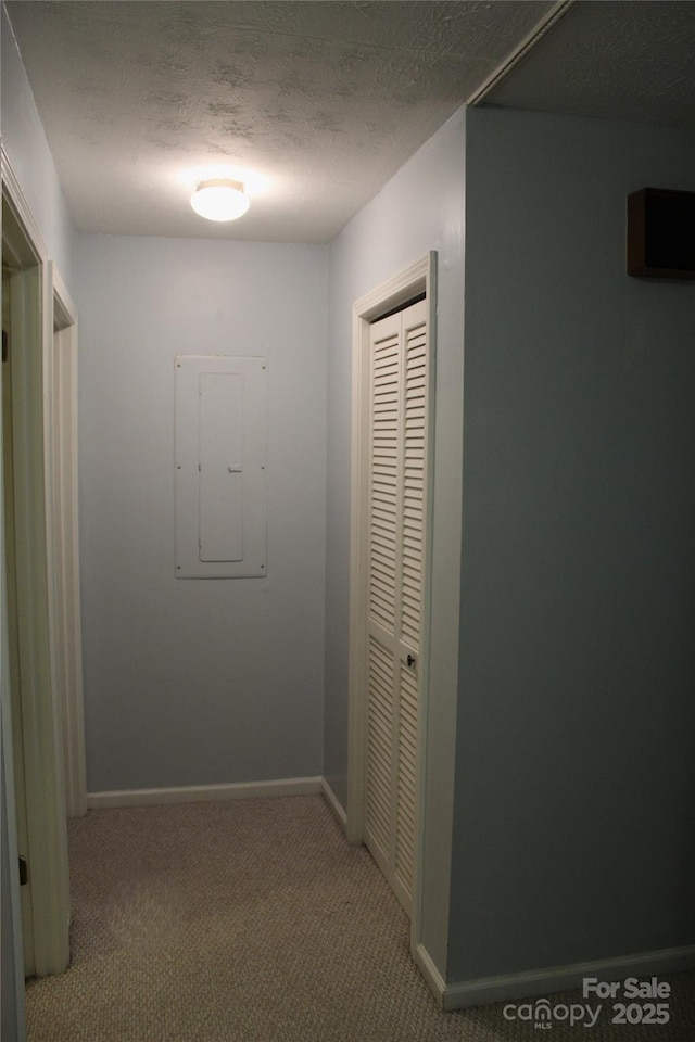 corridor featuring carpet floors, electric panel, and a textured ceiling