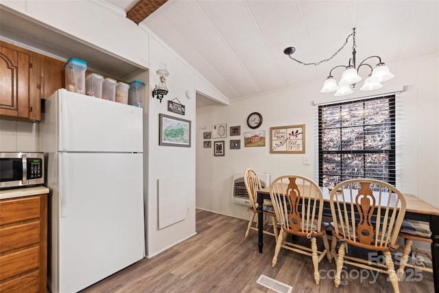 dining area featuring an inviting chandelier, vaulted ceiling, and light hardwood / wood-style flooring