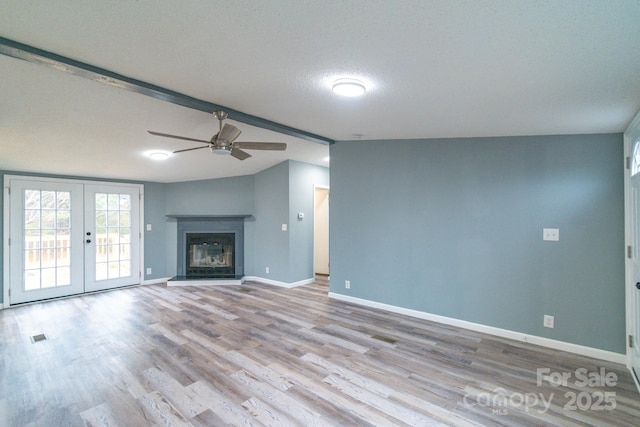 unfurnished living room with ceiling fan, lofted ceiling with beams, a textured ceiling, french doors, and light wood-type flooring