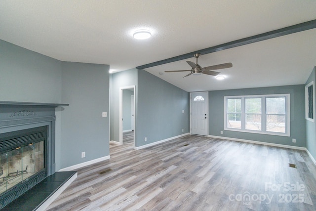 unfurnished living room featuring lofted ceiling with beams, ceiling fan, a textured ceiling, and light wood-type flooring