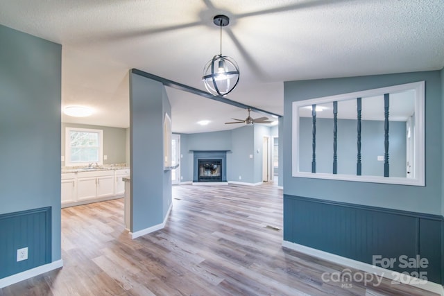 interior space with ceiling fan, sink, light hardwood / wood-style floors, and a textured ceiling