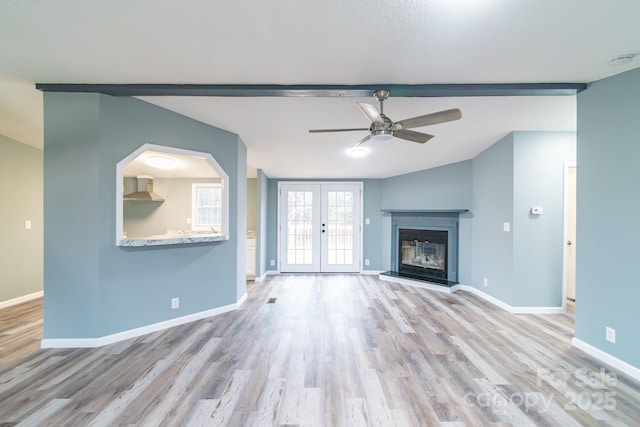 unfurnished living room featuring french doors, ceiling fan, vaulted ceiling, and light wood-type flooring