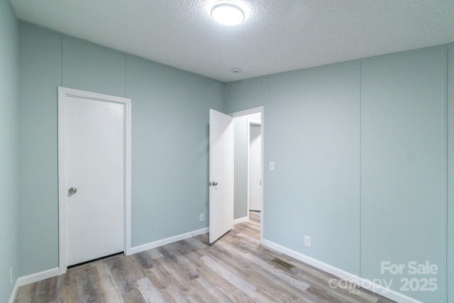 unfurnished bedroom featuring a textured ceiling and light hardwood / wood-style flooring