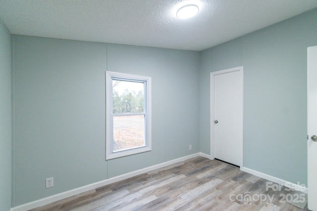 spare room with a textured ceiling and light wood-type flooring