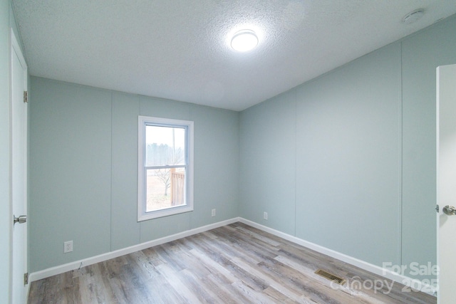 spare room with a textured ceiling and light wood-type flooring