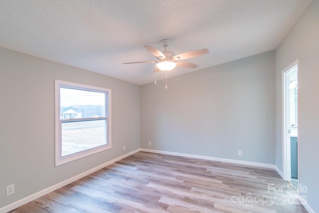 unfurnished room with ceiling fan, a textured ceiling, and light wood-type flooring