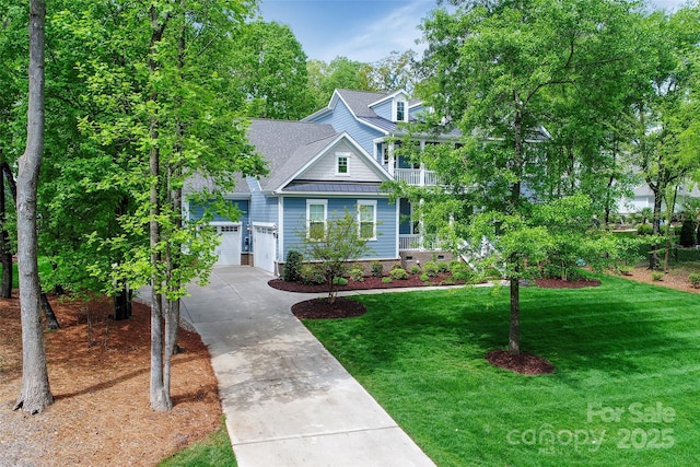 view of front of property with driveway, metal roof, an attached garage, a front yard, and a standing seam roof