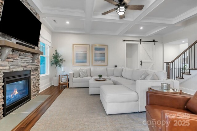 living area featuring ceiling fan, wood finished floors, coffered ceiling, and a barn door