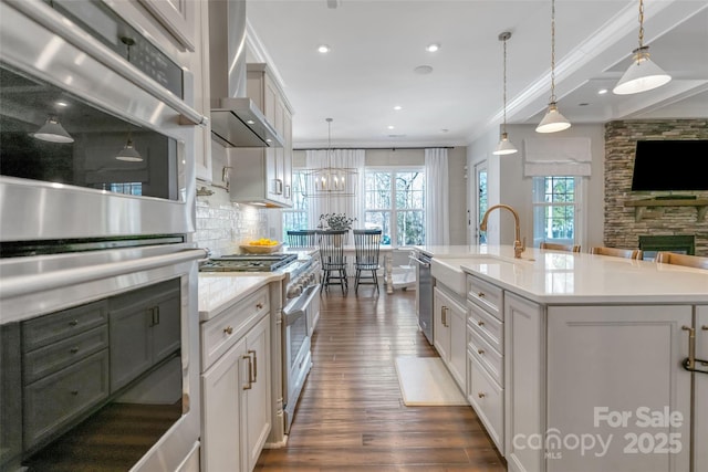 kitchen with decorative backsplash, light countertops, dark wood finished floors, wall chimney exhaust hood, and appliances with stainless steel finishes