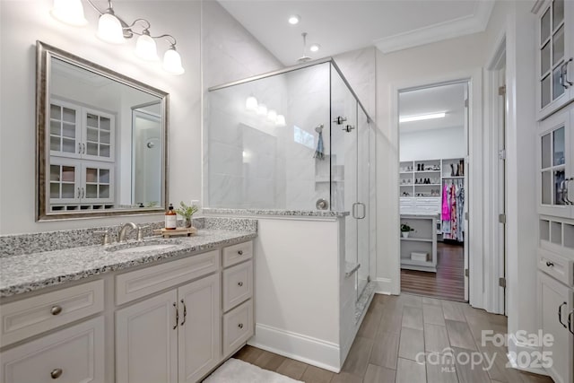 full bathroom with a shower stall, wood finished floors, a spacious closet, vanity, and recessed lighting
