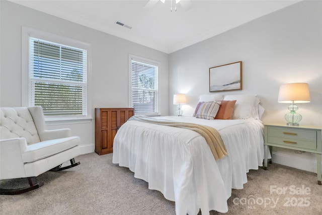 carpeted bedroom featuring ornamental molding, baseboards, visible vents, and ceiling fan