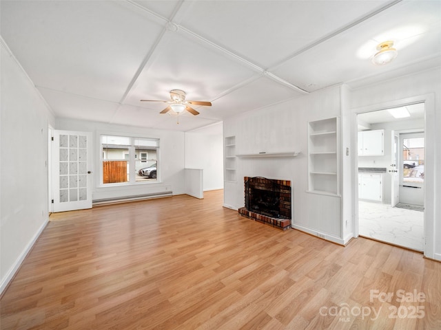 unfurnished living room featuring built in shelves, light hardwood / wood-style flooring, ceiling fan, a fireplace, and a baseboard heating unit