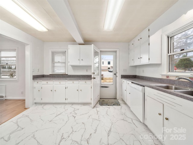 kitchen featuring white dishwasher, sink, and white cabinetry