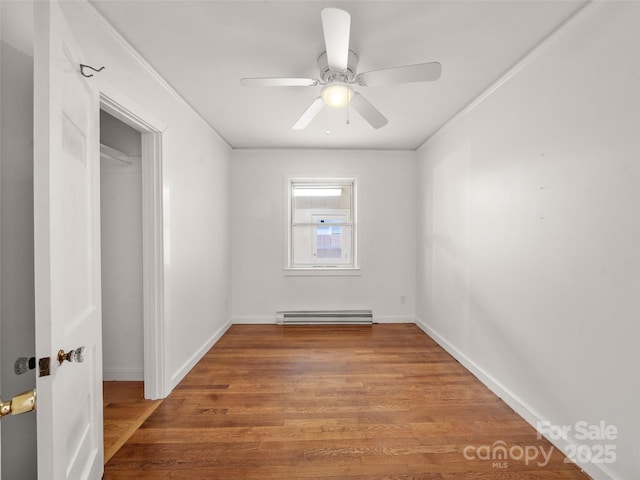 unfurnished room with wood-type flooring, a baseboard heating unit, ceiling fan, and ornamental molding