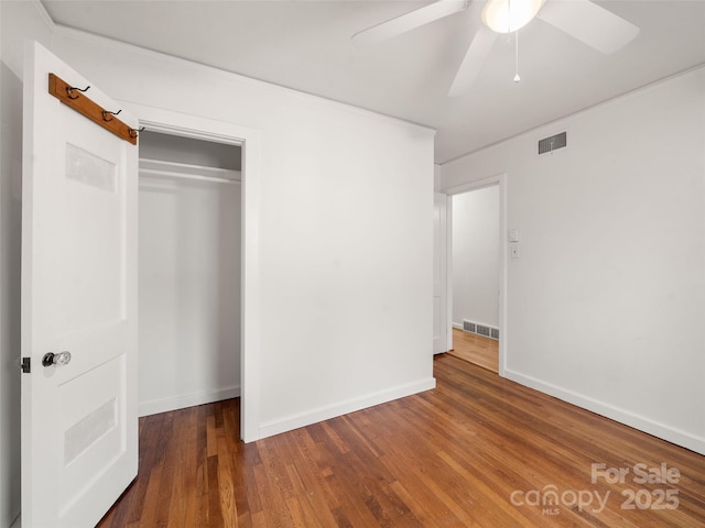 unfurnished bedroom with ceiling fan, dark hardwood / wood-style floors, and a closet