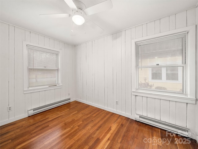 spare room with wood-type flooring, ceiling fan, and baseboard heating