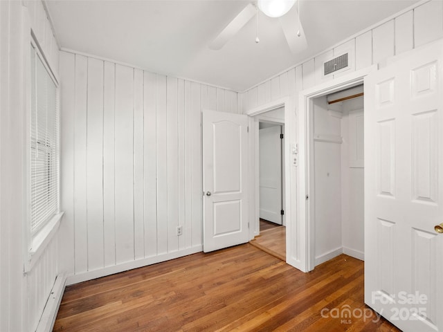 unfurnished bedroom with hardwood / wood-style floors, ceiling fan, and baseboard heating