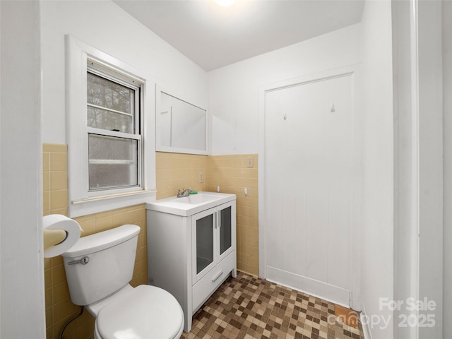 bathroom featuring vanity, toilet, and tile walls