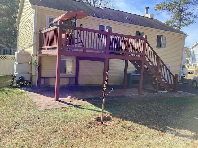 back of property with a wooden deck, a patio area, and a lawn