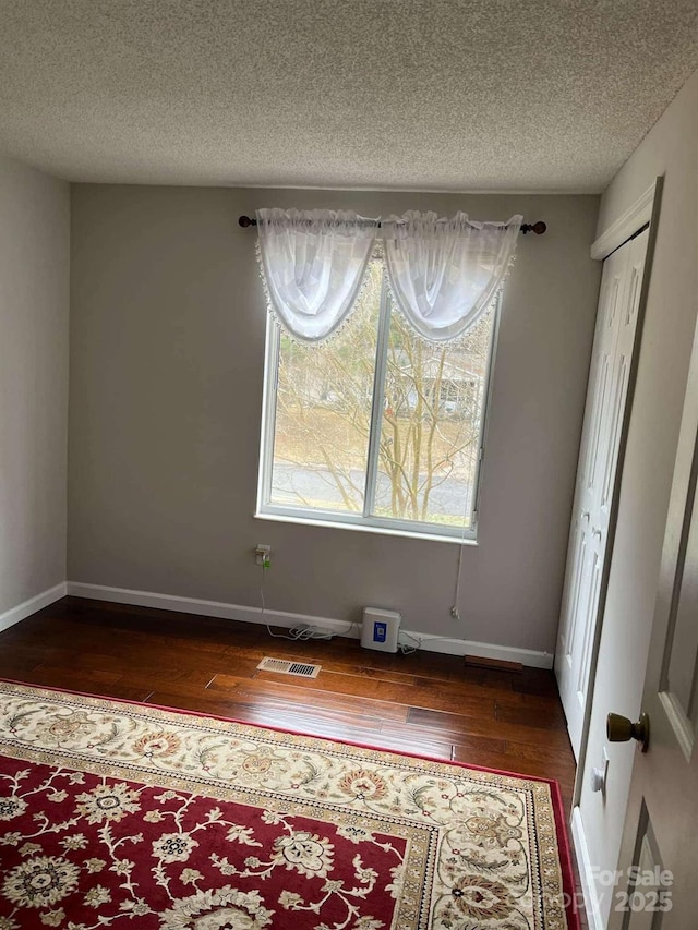 unfurnished room featuring dark wood-type flooring and a textured ceiling