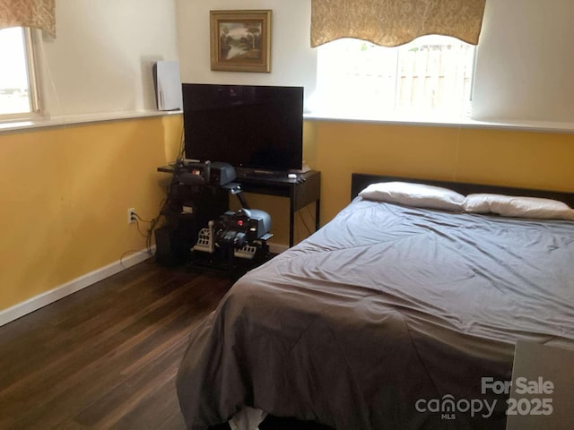 bedroom with multiple windows and dark hardwood / wood-style floors