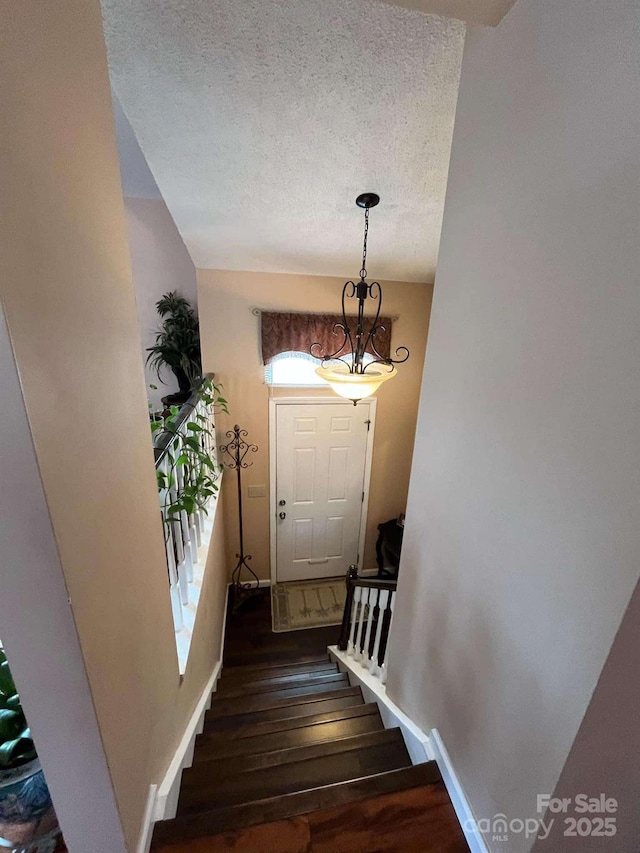 staircase featuring wood-type flooring and a textured ceiling