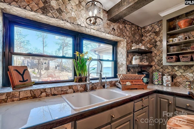 kitchen with a notable chandelier, a sink, gray cabinets, beam ceiling, and open shelves