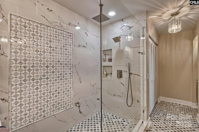 bathroom featuring tiled shower, tile patterned flooring, and baseboards