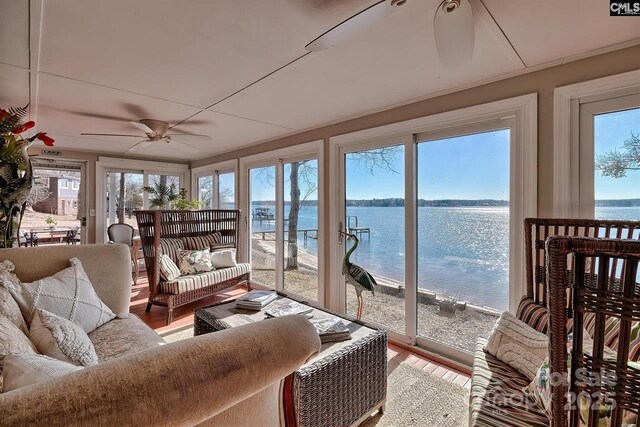 sunroom / solarium with a ceiling fan and a water view