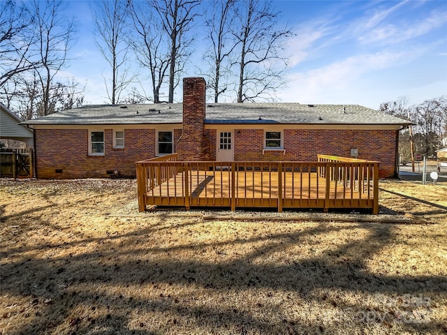 rear view of house featuring a wooden deck and a lawn