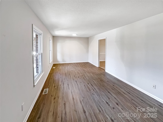 unfurnished room featuring dark hardwood / wood-style floors and a textured ceiling