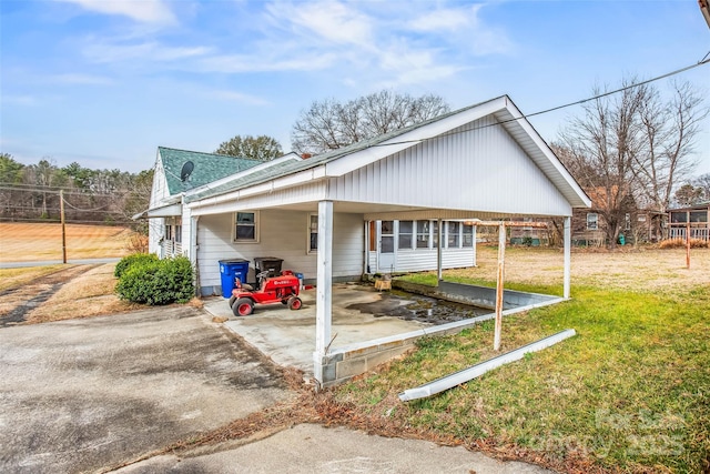 exterior space featuring a front yard, a carport, and a sunroom