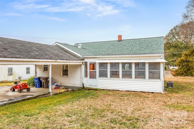 back of property featuring a sunroom, central AC, a patio area, and a lawn