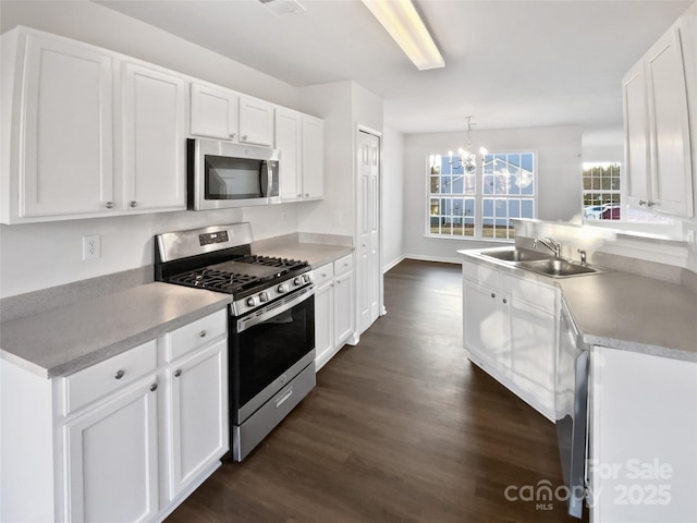 kitchen with appliances with stainless steel finishes, sink, pendant lighting, and white cabinets