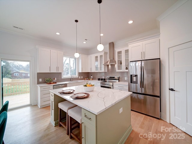 kitchen with white cabinetry, stainless steel appliances, a center island, and wall chimney exhaust hood