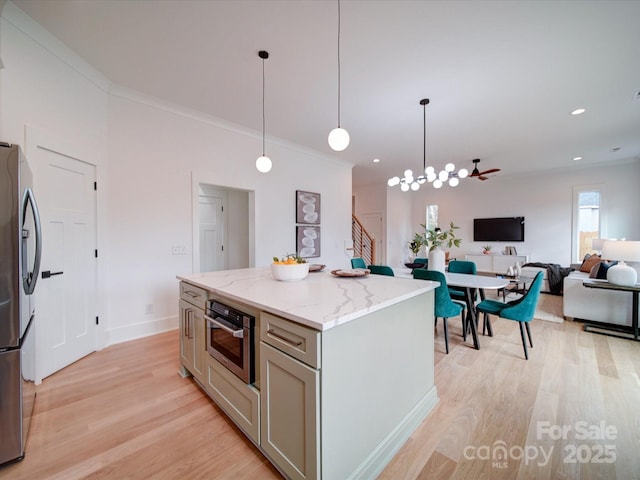 kitchen featuring light stone counters, hanging light fixtures, light wood-type flooring, a kitchen island, and stainless steel appliances