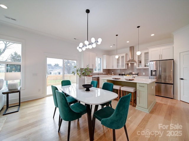 dining space featuring sink, ornamental molding, light hardwood / wood-style floors, and a chandelier