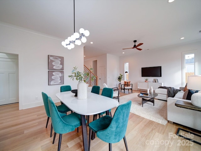 dining room featuring ornamental molding, ceiling fan with notable chandelier, and light hardwood / wood-style flooring