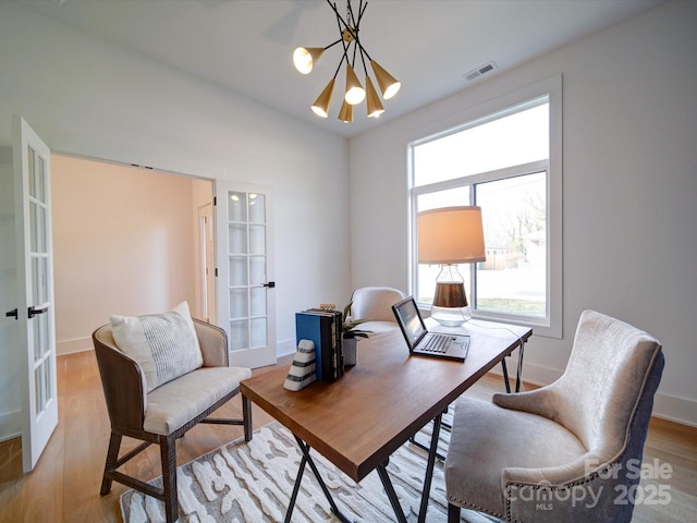 office featuring french doors, a chandelier, and light hardwood / wood-style flooring