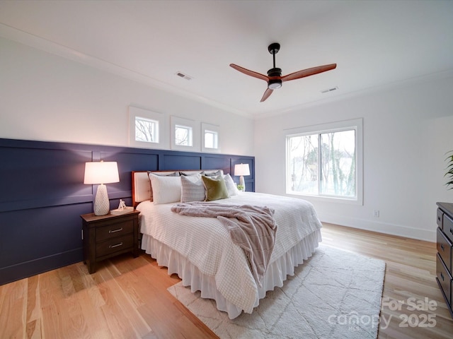 bedroom with multiple windows, crown molding, ceiling fan, and light wood-type flooring