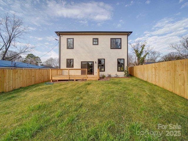 rear view of house featuring a wooden deck and a lawn